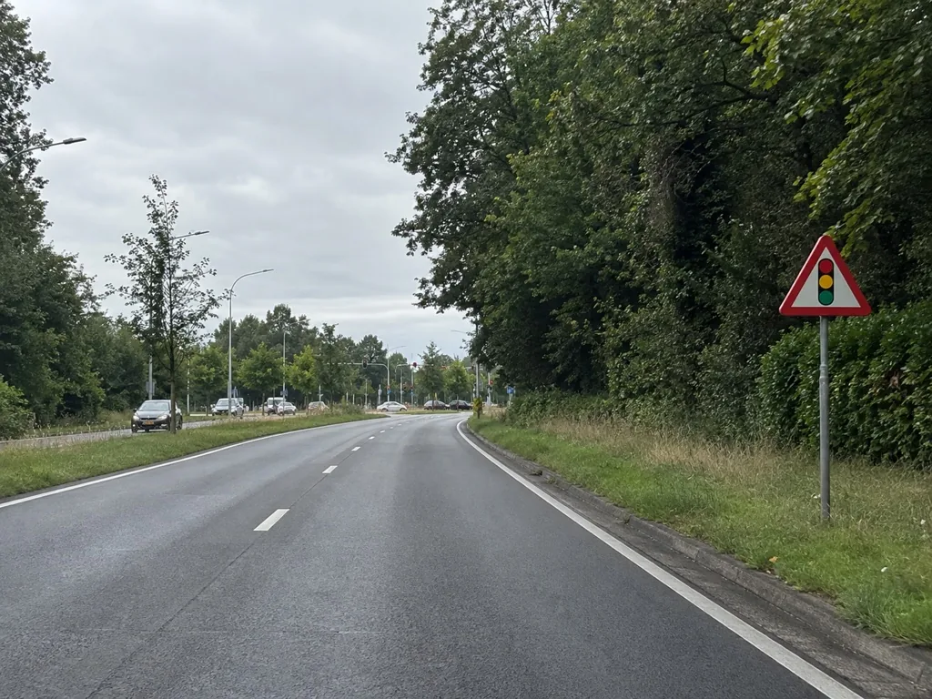 Een gevaarsbord langs een weg voor een kruispunt.