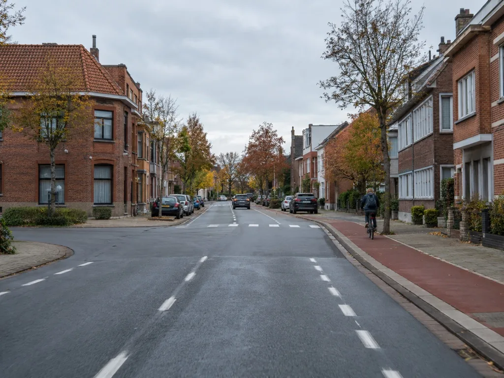 Kruispunt in een stad met een fietser op het rode fietspad rechts.