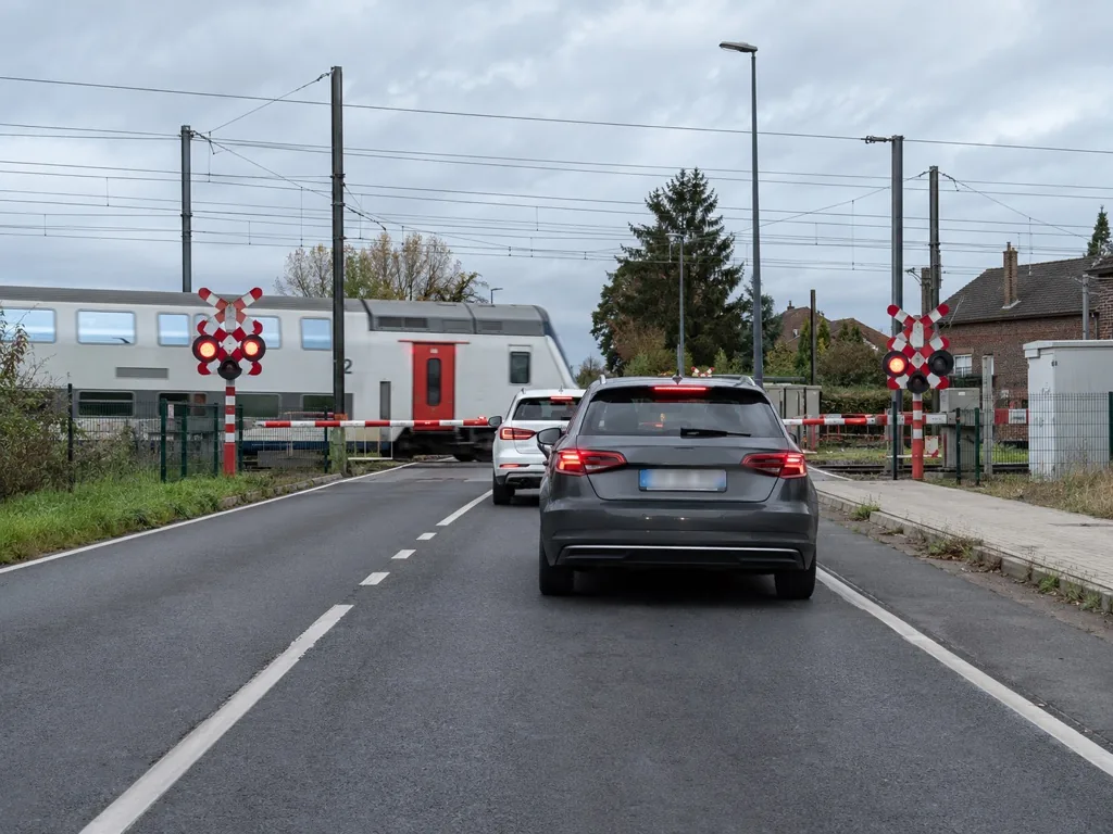 Een gesloten overweg met neergelaten bomen en wachtende auto's.
